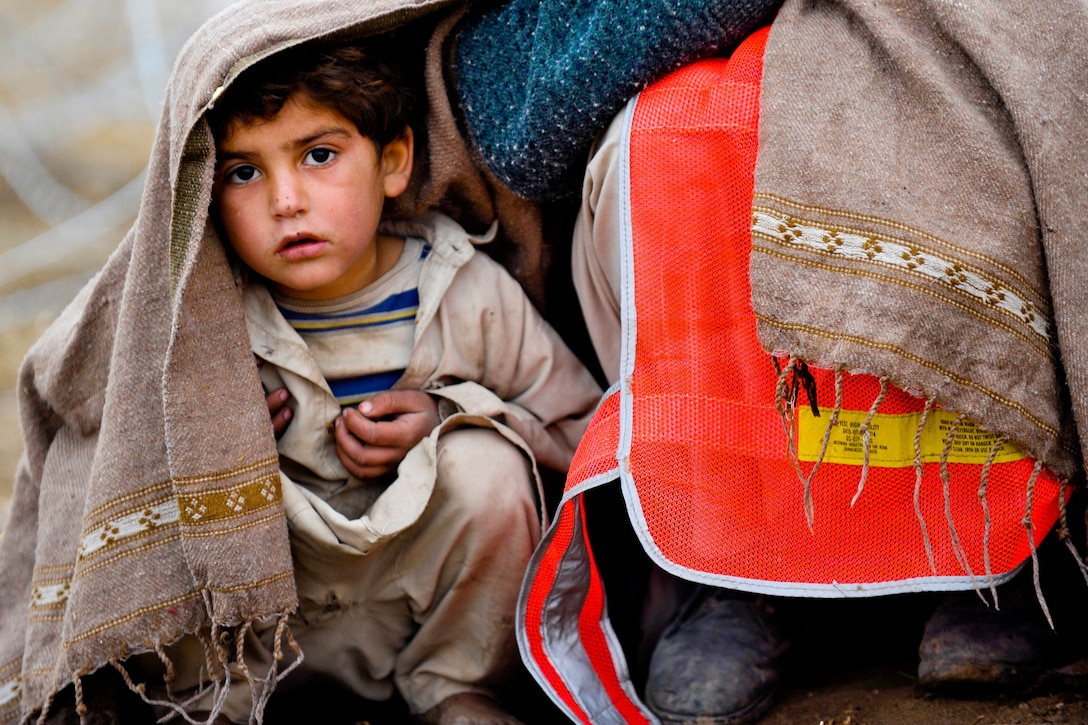A young Afghan boy accompanies his father who is participating as a day laborer in the Cash for Work program outside Stronghold Dog, Afghanistan, Jan. 29, 2011.