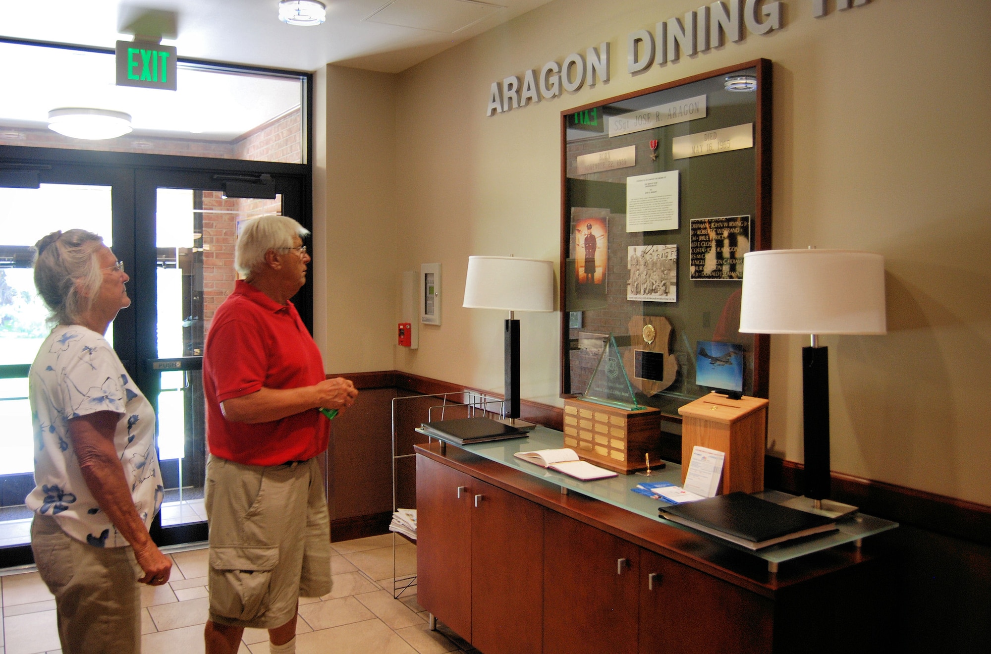 Leo and Bette Hrdlicka take time to look at the Staff Sgt. Jose Aragon dedication display in the Aragon Dining Hall, June 24. Sergeant Aragon distinguished himself by meritorious achievement while engaged in ground support of Tactical Air Operations against an opposing armed force at Bien Hoa Air Base, Republic of Vietnam on May 16, 1965. (Air Force photo/Airman 1st Class Jessica Hines)