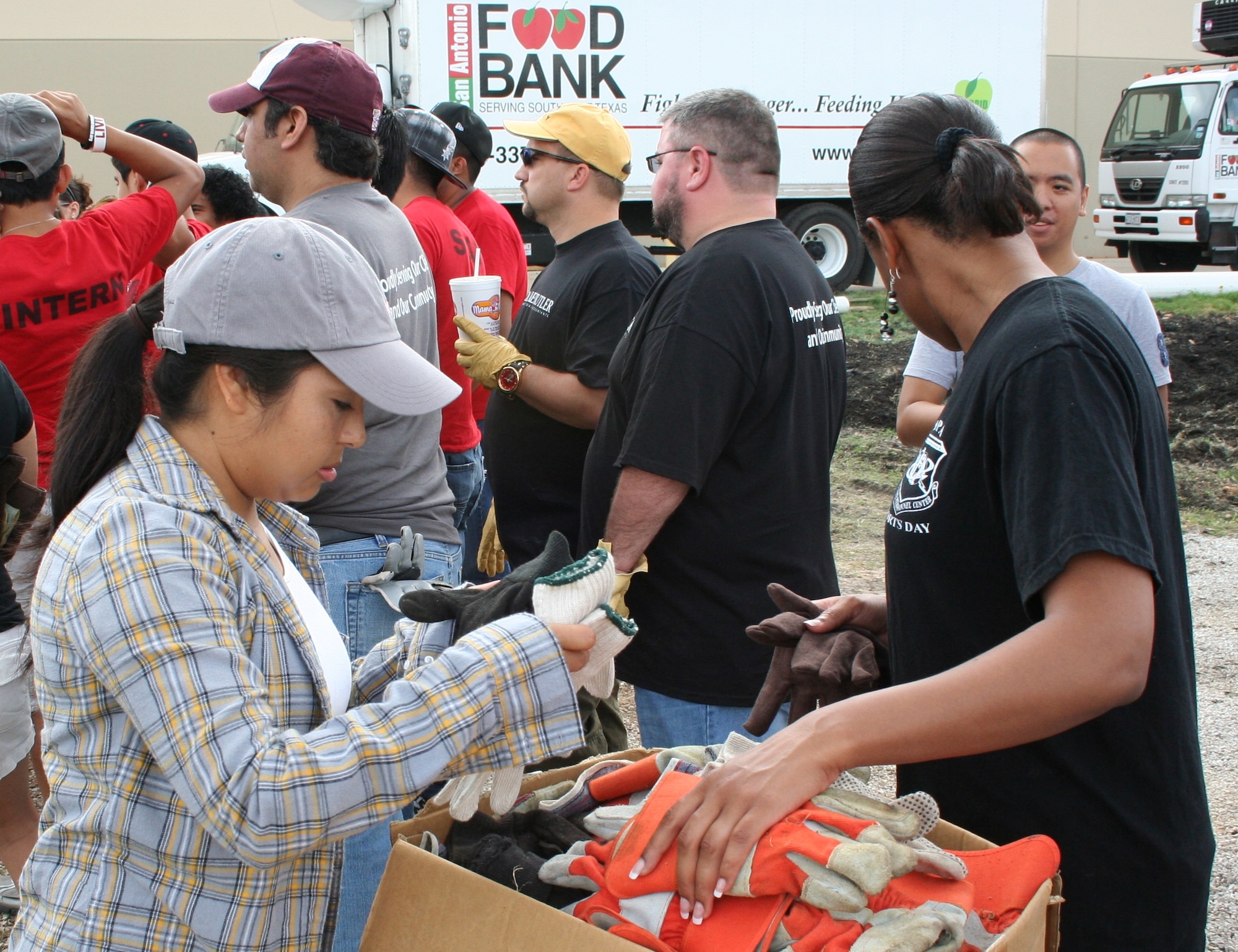 Tech. Sgt. Dolores Barrita, AFPC special duty assignments, selects a pair of gloves before helping harvest produce at the San Antonio Food Bank. (U.S. Air Force photo/Debbie. Gildea)
