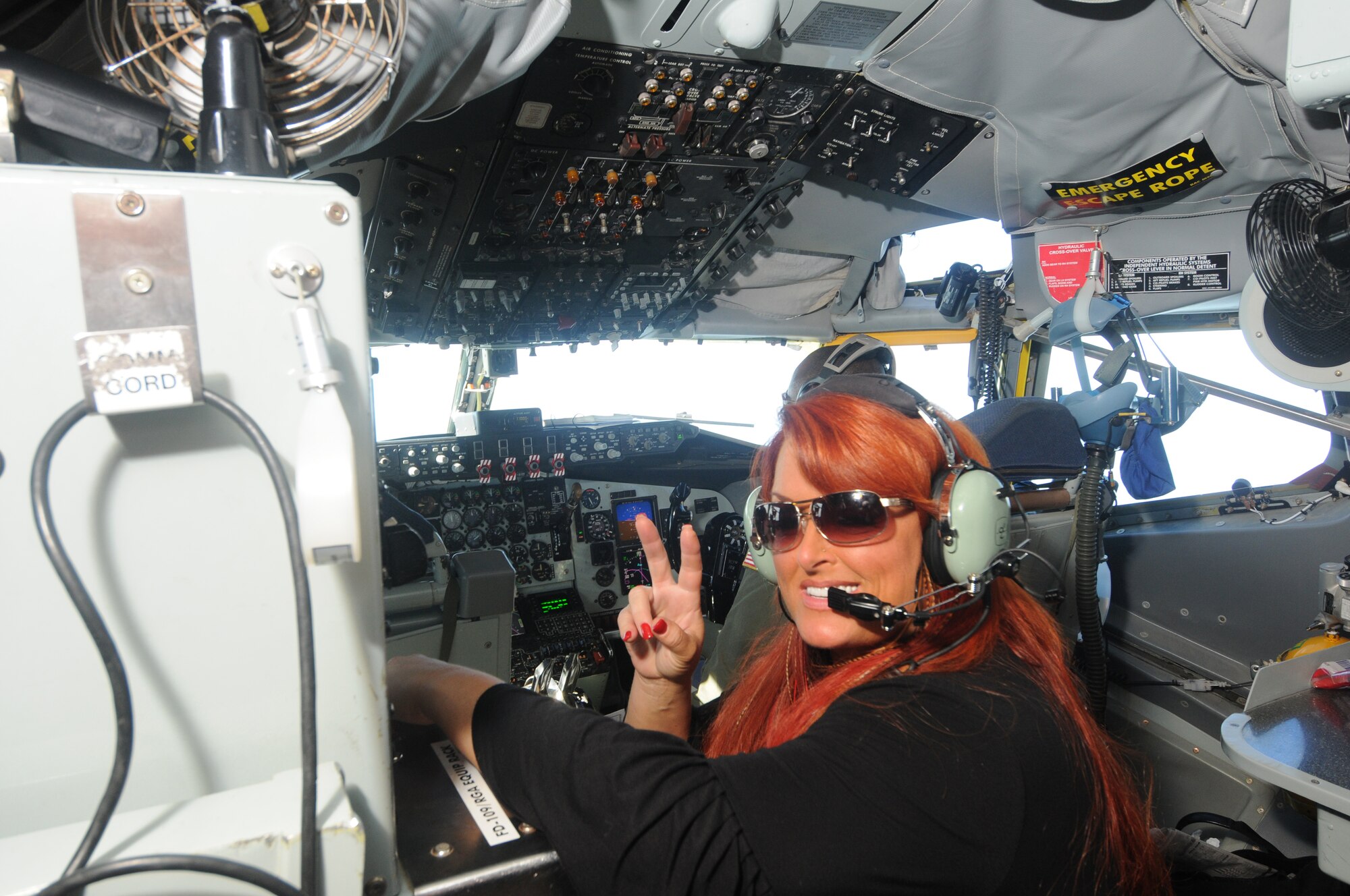 Wynonna Judd flashes the peace sign June 30, 2011, during an orientation flight aboard a KC-135 Stratotanker somewhere over the southeastern United States. Ms. Judd and her family had the opportunity to watch as the KC-135, from the 916th Air Refueling Wing, Seymour Johnson Air Force Base, N.C., refueled a pair of F-15 Strike Eagles, before returning to Robins Air Force Base, Ga. Ms Judd, a 5-time Grammy Award winning county singer, is the featured guest artists for the July 1 Independence Day Concert in Warner Robins, Ga. (U.S. Air Force photo/Ken Hackman)