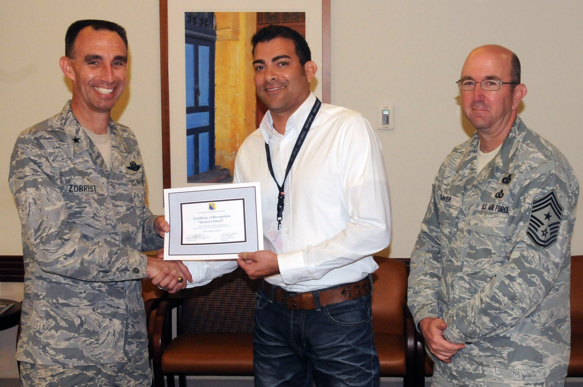 Brig. Gen. Scott J. Zobrist, 31st Fighter Wing commander, along with 31st FW Command Chief Master Sgt. Jeffrey Craver, congratulate Juan Gutierrez, 31st Medical Operations Squadron mental health ward clerk, on his selection as one of Aviano's Finest. (U.S. Air Force photo/Airman LaVel Sterling)