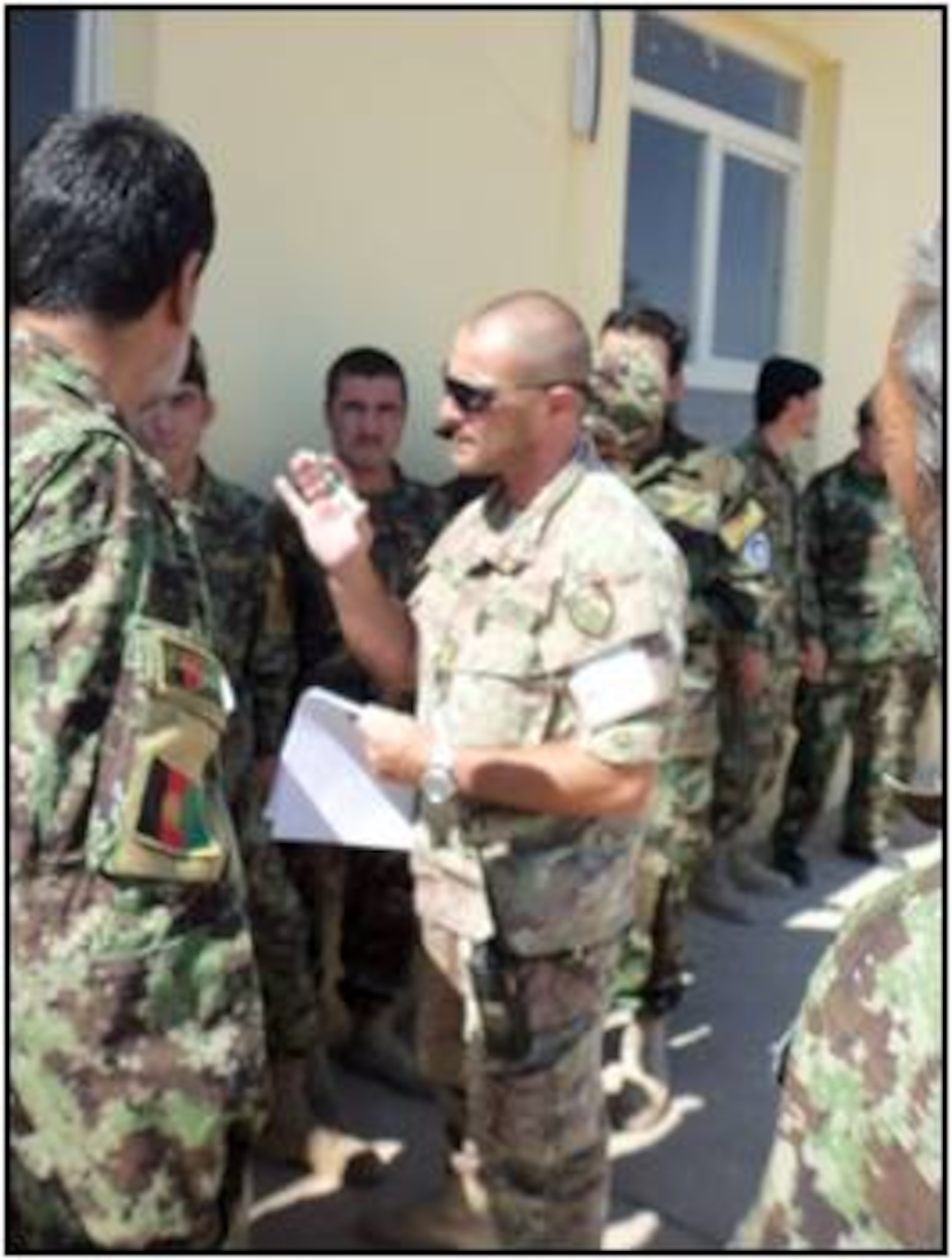SHINDAND, Afghanistan – Italian Air Force Chief Gaetano Picierro, works with members of the AAF while facilitating the literacy portion of the promotion exam to AAF members June 27.  In addition to the literacy test, AAF members also finished the physical fitness portion as well.  According to personnel officials, promotion testing for the ranks of E-4 to E-5 and E-5 to E-6 are the only ranks handled directly by the AAF per Ministry of Defence policy with all other ranks handled centrally through the MoD on an annual basis.  (U.S. Air Force courtesy photo)   

