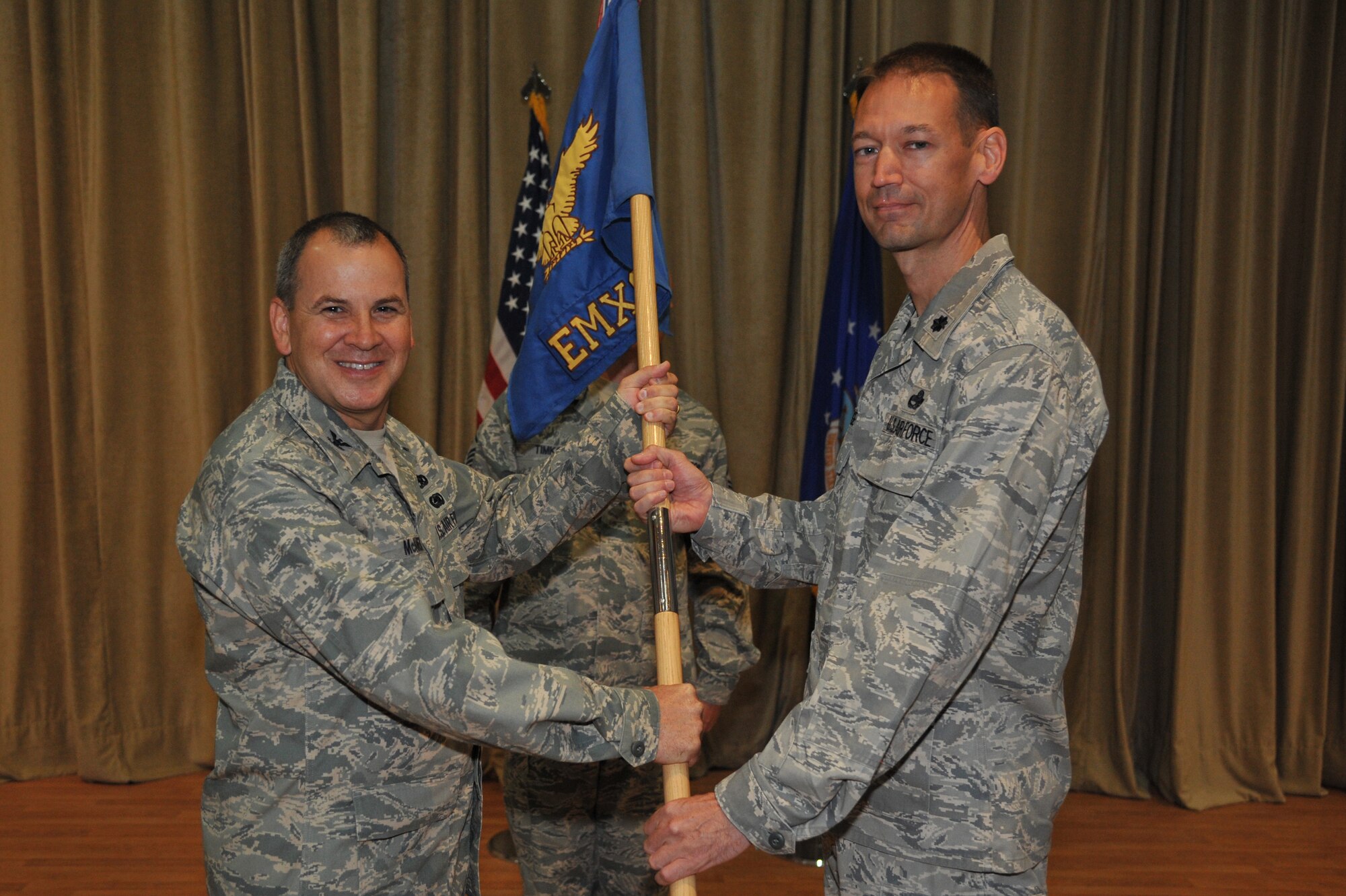 Col. Paul McAneny, 386th Expeditionary Maintenance Group commander, left, passes the 386th Expeditionary Maintenance Squadron guide-on to Lt. Col. Allan Hodge during a change of command ceremony July 1 at an undisclosed location in Southwest Asia. Colonel Hodge assumed command of the 386th EMXS from Major Michael Campos. (U.S. Air Force photo by Master Sgt. Carlotta Holley)