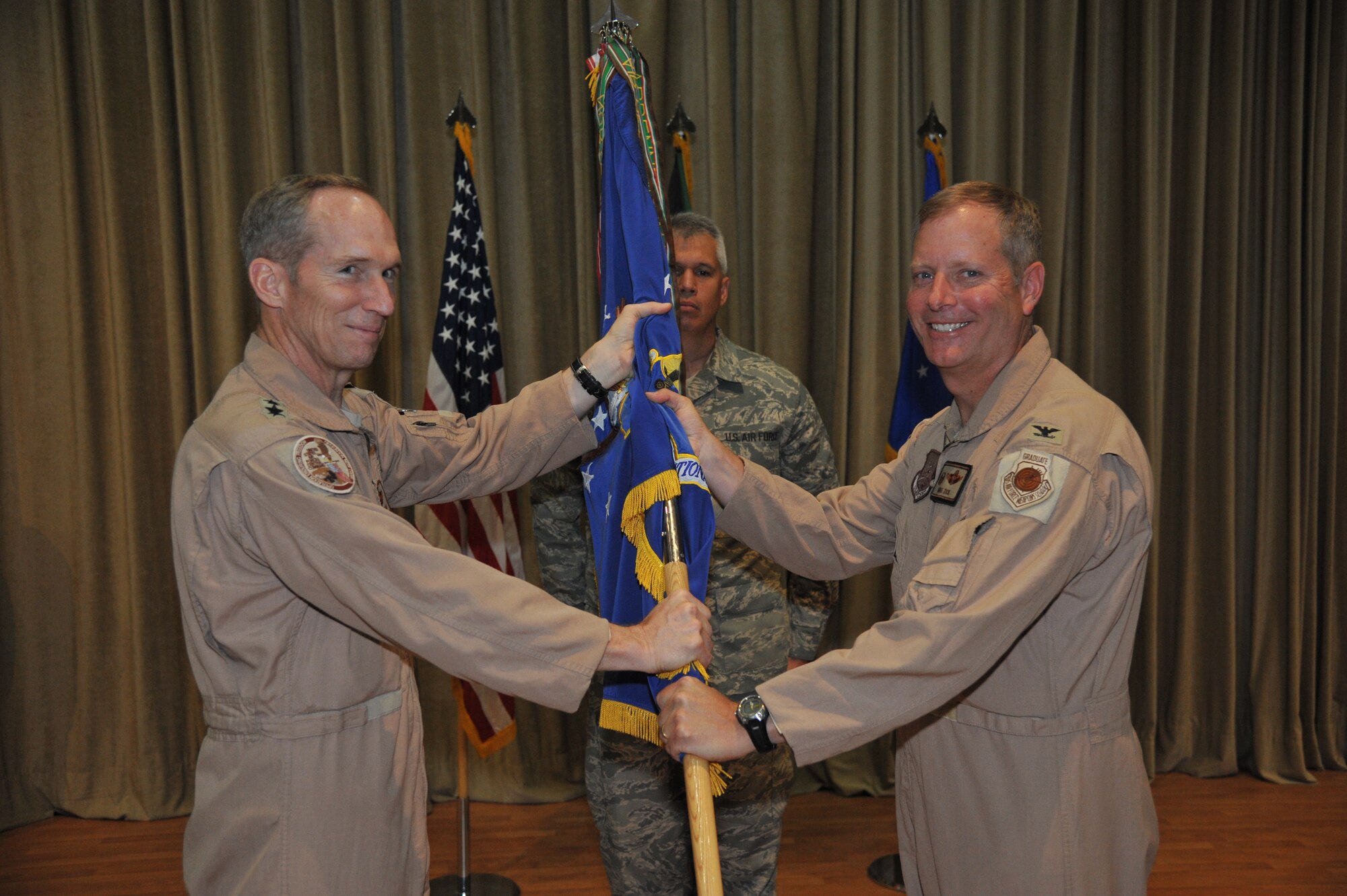 General Mike Hostage, Air Forces Central commander, left, passes the 386th Air Expeditionary Wing guide-on to Col. Michael Zick during a change of command ceremony June 30 at an undisclosed location in Southwest Asia. Colonel Zick assumed command of the 386th AEW from Col. Mordente. (U.S. Air Force photo by Master Sgt. Carlotta Holley)