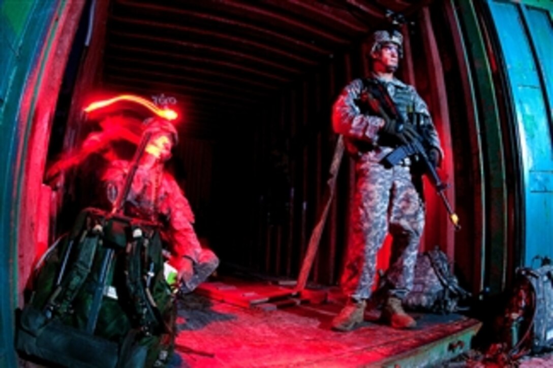 An Army paratrooper provides security as another paratrooper uses a field radio to keep in touch with other elements of his unit during a joint operational access exercise at Fort Bragg, N.C., on June 27, 2011.  The paratroopers are assigned to the 82nd Airborne Division?s 1st Brigade Combat Team.  The three-day exercise began with a mass tactical parachute drop of vehicles and paratroopers.  