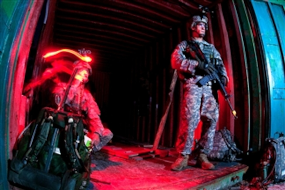 An Army paratrooper provides security as another paratrooper uses a field radio to keep in touch with other elements of his unit during a joint operational access exercise at Fort Bragg, N.C., on June 27, 2011.  The paratroopers are assigned to the 82nd Airborne Division?s 1st Brigade Combat Team.  The three-day exercise began with a mass tactical parachute drop of vehicles and paratroopers.  