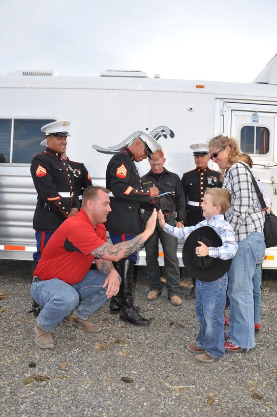 The members of the Marine Corps Mounted Color Guard aboard Marine Corps Logistics Base Barstow greet and excite guests at the Cody Rodeo Stampede at Cody, Wyo., July 3. The MCG presented the National Colors during the opening ceremony every night of the Professional Rodeo Cowboys Association rodeo.