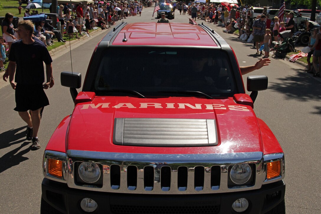 Staff Sgt. Timothy Anderson, 31, from Fall Creek, Wis., waves to residents while driving a branded H3 in the Forest Lake Fourth of July Annual Parade. Anderson and a handful of aspiring Marines handed out more than 1,500 stickers and pencils to children along the parade route. Anderson is a recruiter out of the Coon Rapids, Minn., office. For additional imagery from the event, visit www.facebook.com/rstwincities.