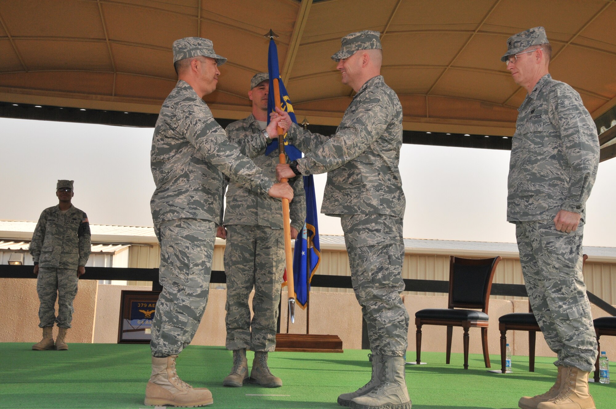 Col. Shannon Jurrens accepts the 64th Air Expeditionary Group guidon from Col. Giovanni K. Tuck, 379th Air Expeditionary Wing commander, during a change of command ceremony, June 29, in Southwest Asia. During the ceremony, Colonel Jurrens assumed command of the group from Col. Gary Nelson. The 64 AEG is a geographically separated unit of the 379 AEW, and provides security and base support to an undisclosed location in the Middle East.  (U.S. Air Force photo/Master Sgt. Mike Hammond)