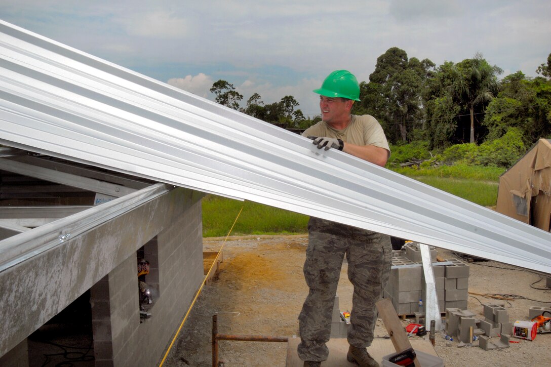 U.S. Air Force Master Sgt. Allen Wolf slides additional roof sheeting into place at the Alkmaar Clinic in Paramaribo, Suriname, July 3, 2011. Wolf is an 
operations flight craftsman assigned to the 114th Civil Engineer Squadron.