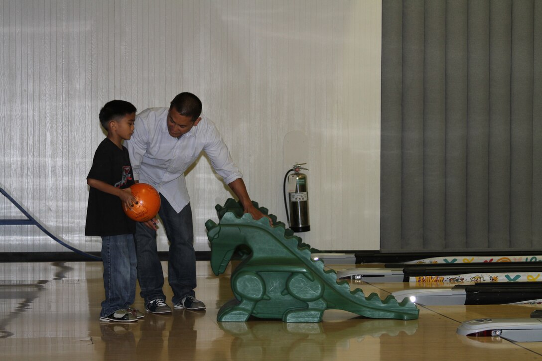 A man shows a young boy how to like up his shot at the depot recreation center. Some of the most popular amenities the recreation center offers include: free arcade games; a gamer’s center that includes an XBox 360, Playstation 3; free wireless internet access; a movie theater; bowling and a snack bar.