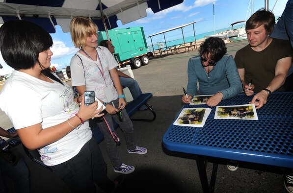 Fans wait as the lead singer of the Plain White T's, Tom Higgenson, autographs a band photo at Hickam Harbor on July 4. The festivities, sponsored by MWR, included bouncy houses,  food vendors and a free concert by the Plain White T's.  Hundreds of families and military members camped at the harbor the night before and stayed to enjoy the brilliant display of Fourth of July fireworks that evening. (U.S. Air Force photo/Senior Airman Lauren Main)