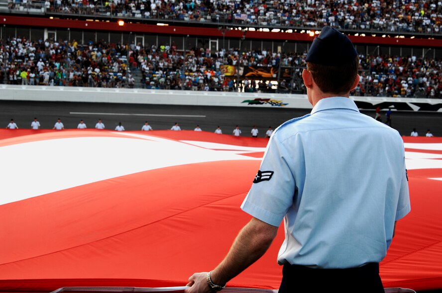 An Airman from Moody Air Force Base, Ga., holds an American flag measuring 300 feet by 150 feet July 2, 2011, at the Coke Zero 400 at Daytona Beach, Fla. Air Force recruiters use NASCAR events to publicize the benefits of Air Force life and appeal to youth interested in mechanical jobs. (U.S. Air Force photo by Airman 1st Class Brigitte N. Brantley/Released)