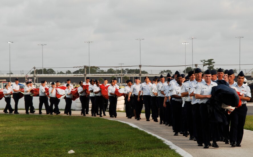 U.S. Air Force Airmen and cadets walk a massive American flag onto the infield July 2, 2011, at the Coke Zero 400 at Daytona Beach, Fla., before a live and broadcast crowd of more than seven million people. Air Force recruiters use NASCAR events as a way to appeal to youth who may be interested in a mechanically-focused job such as an avionics specialist or crew chief. (U.S. Air Force photo by Airman 1st Class Brigitte N. Brantley/Released)
