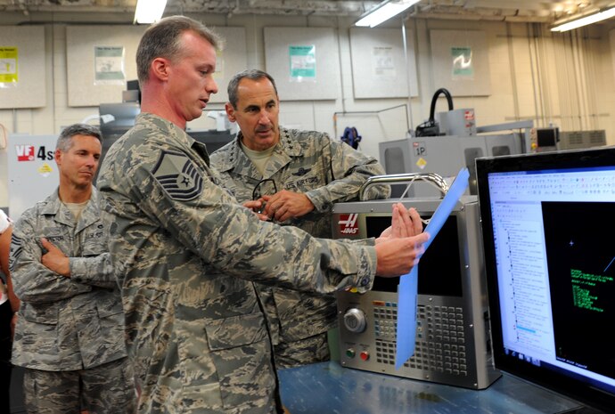 Master Sgt. Kevin Brackett shows Gen. Raymond E. Johns Jr. how a parts program is created at the Metals Tech Shop at Joint Base Charleston - Air Base June 29. Johns toured JB CHS- AB and Weapons Station during his two day visit. Johns is the Air Mobility Command commander and Brackett is a machinist with the 315th Mantenance Group.  (U.S. Air Force photo/ Staff Sgt. Nicole Mickle) 