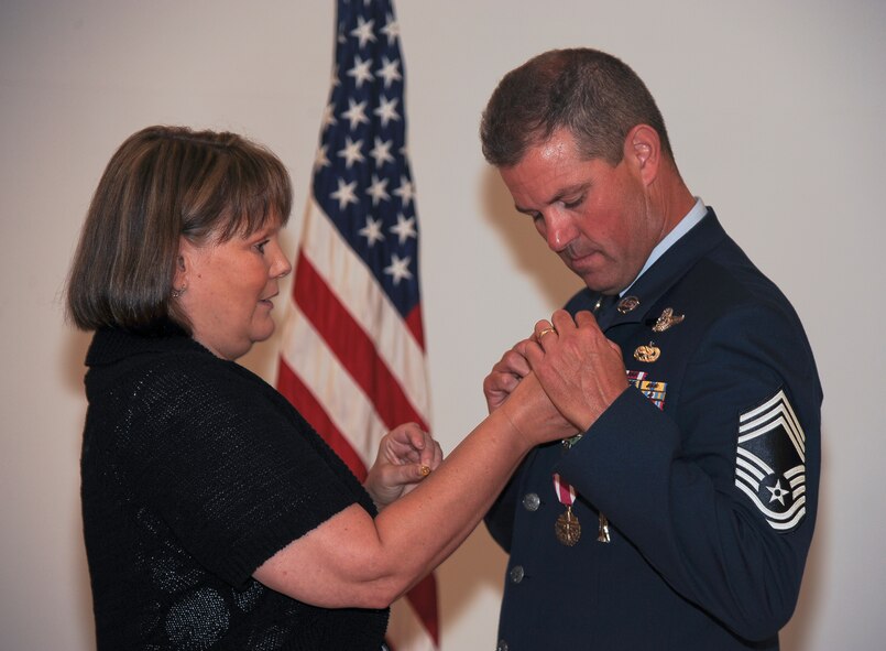 Beverley Stone fastens a retirement pin onto her husband, U.S. Air Force Chief Master Sgt. Michael Stone, 347th Rescue Group chief enlisted manager, during a ceremony at Moody Air Force Base, Ga., June 30, 2011. Mrs. Stone was one of three family members who attended the ceremony of Chief Stone’s retirement. (U.S. Air Force photo by Airman 1st Class Paul Francis/Released)