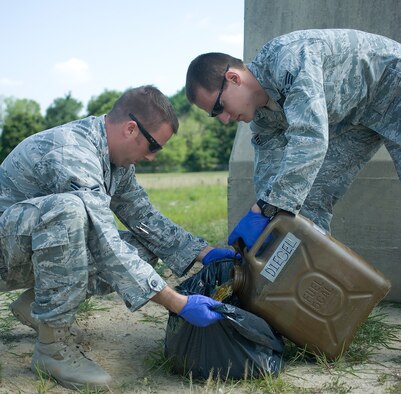 Airman 1st Class Gregg Lowry Jr. (left) and Senior Airman Benjamin McGovern, 436th Civil Engineer Squadron explosive ordnance disposal technicians, work together to pour diesel fuel into a trash bag June 30, 2011, at Dover Air Force Base, Del. This was done as a part of training for Team Dover’s EOD team to learn the effective use of explosives. (U.S. Air Force Photo/Airman 1st Class Jacob Morgan)