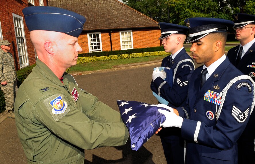 RAF MILDENHALL, England – Staff Sgt. Emmanuel Santillan, RAF Mildenhall Honor Guard, passes the American flag to Col. Bill DeMarco, 100th Operations Group commander, during the retreat ceremony here July 1, 2011. Retreat signals the end of the duty day while also paying respect to the flag. (U.S. Air Force photo/Senior Airman Ethan Morgan)