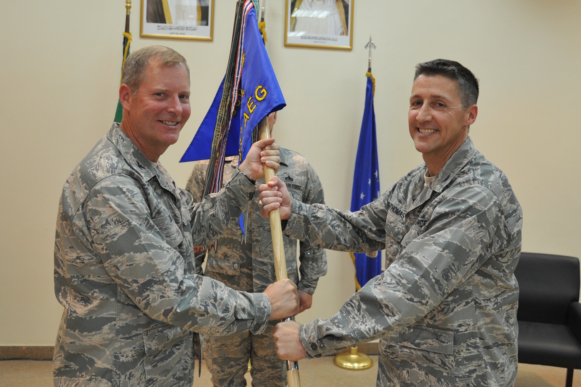 Col. Michael Zick, 386th Air Expeditionary Wing commander, left, passes the 387th Air Expeditionary Group guide-on to Col. Scott DeThomas during a change of command ceremony July 5 at an undisclosed location in Southwest Asia. Colonel DeThomas assumed command of the 387th AEG from Col. Tal Metzgar. (U.S. Air Force photo by Master Sgt. Carlotta Holley)