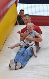 Lt. jg. Brett Mattison and his son Alex go down an inflatable slide during Freedom Fest 2011 at Joint Base Charleston – Weapons Station July 1. Mattison is an instructor at the Navy Nuclear Power Training Command. (U.S. Air Force photo/Airman Jared Trimarchi)