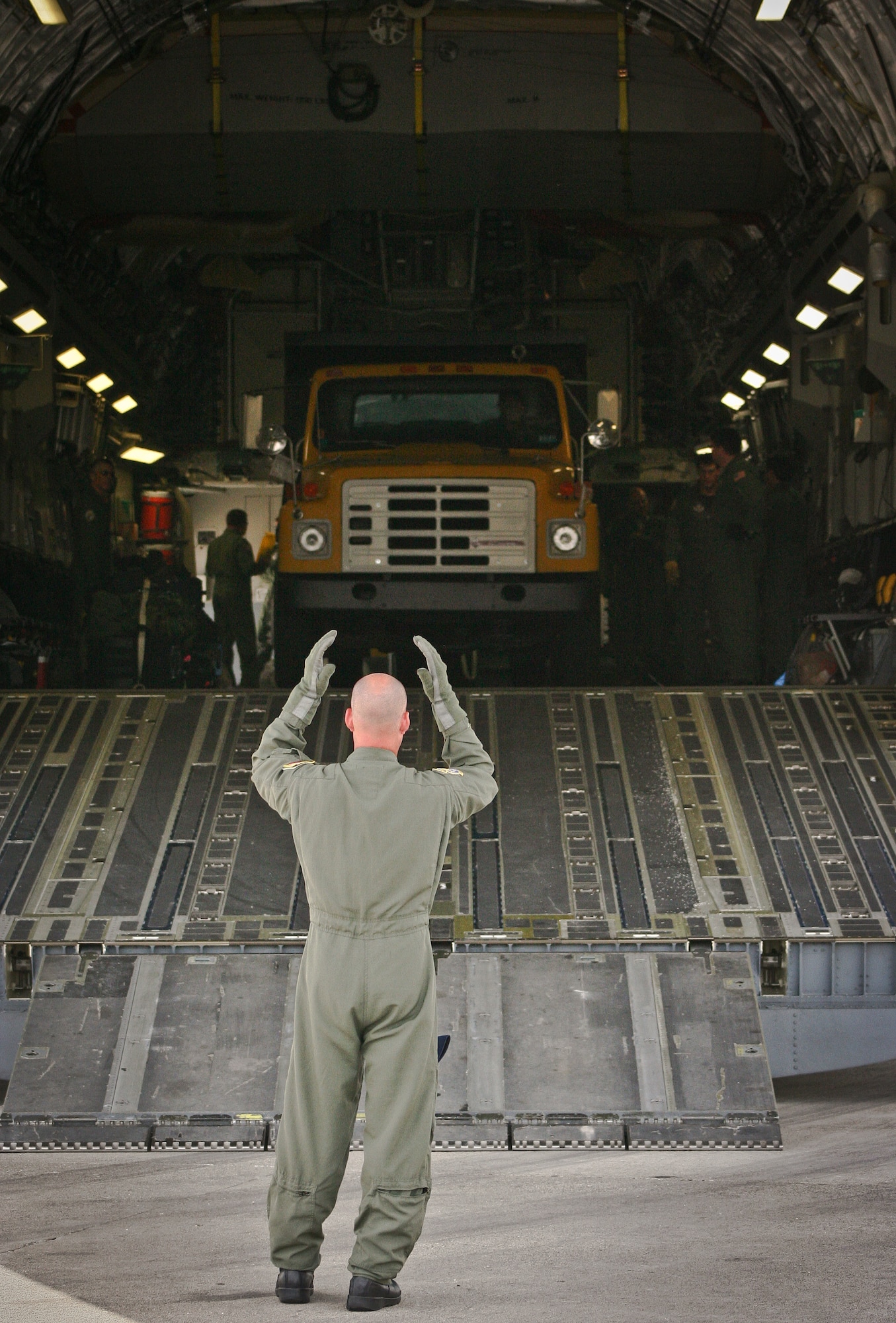 Technical Sergeant Arrin Baker of 300th Airlift Squadron marshals a dump truck out of the back of a C-17 Globemaster III during a humanitarian aid download in Haiti on July 1, 2011.