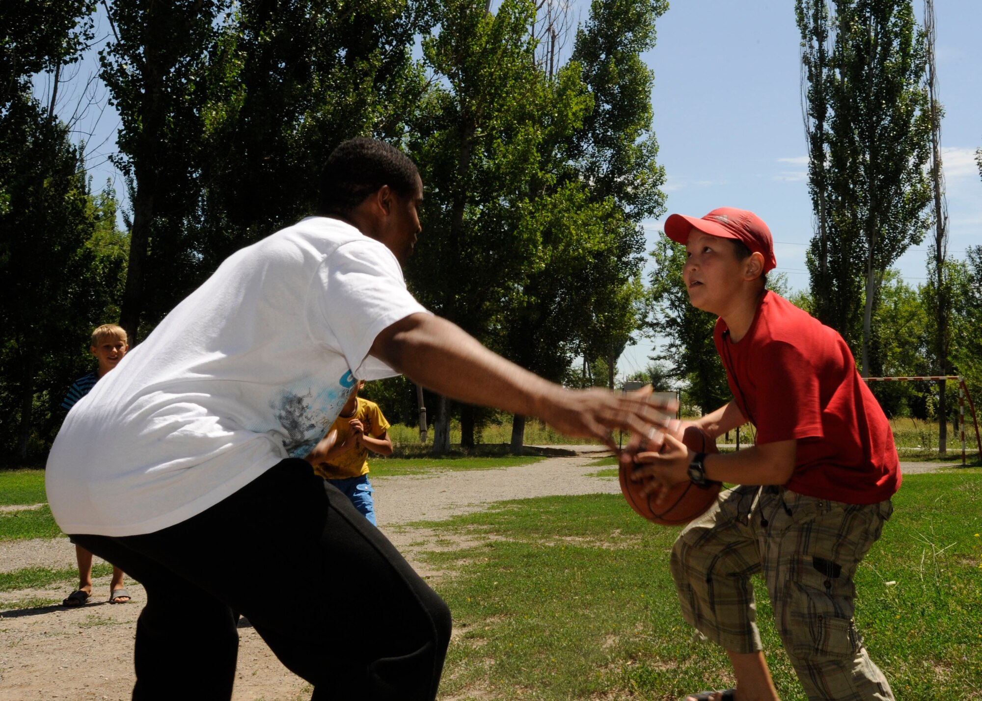 KAMYSHANOVKA, Kyrgyzstan – Staff Sgt. Diamond Edwards tries to block the shot of a local child as the two play a game of basketball here July 1. After donating a public address system to the village, Airmen from the Transit Center at Manas’ 376th Expeditionary Communications Squadron played games of basketball, volleyball, American football and Frisbee with village children. Edwards is a communications project manager deployed from Davis-Monthan Air Force Base, Ariz. (U.S. Air Force photo/Tech. Sgt. Tammie Moore)