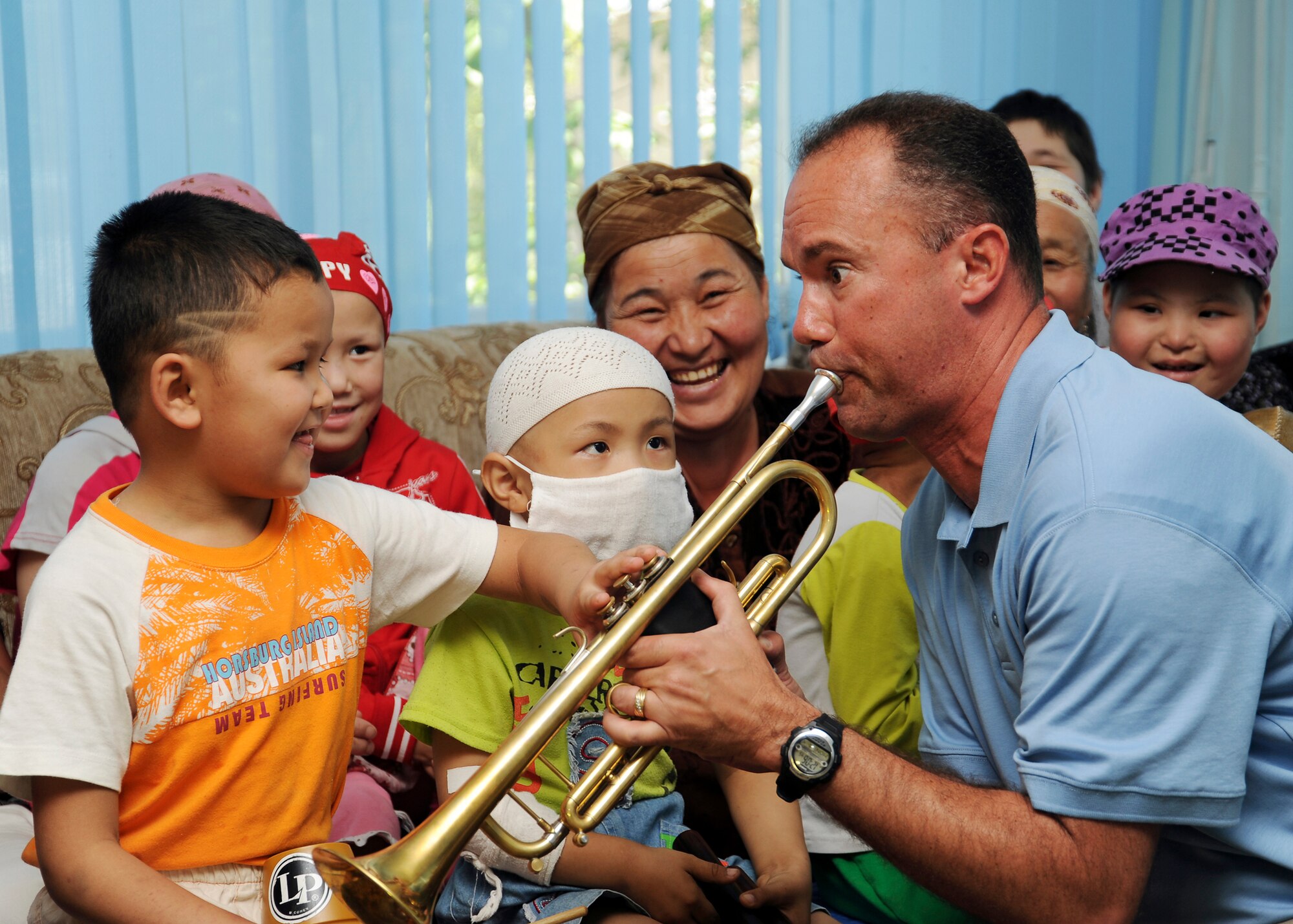 U.S. Air Force Maj. Eric Patterson, a trumpet player with the Air Forces Central Expeditionary Band "Blue Hawk" from Naval Air Station Fort Worth Joint Reserve Base, Texas, plays his trumpet while a young child pushes the pistons down during a visit to a children's cancer center in Bishkek, Kyrgyzstan, July 4, 2011. The AFCENT Band builds troop morale and public diplomacy while touring the area of responsibility. (U.S. Air Force photo by Staff Sgt. Matthew Smith)

