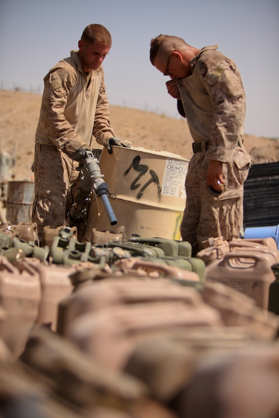 Corporal Nicholas Lavery (left) of Akron, Ohio, refuels dozens of fuel cans during a convoy mission. He and the two other fuel drivers with the logistics train, 3rd Battalion, 2nd Marine Regiment, have collectively supplied the unit with more than 250,000 gallons of fuel.::r::::n::::r::::n::::r::::n::