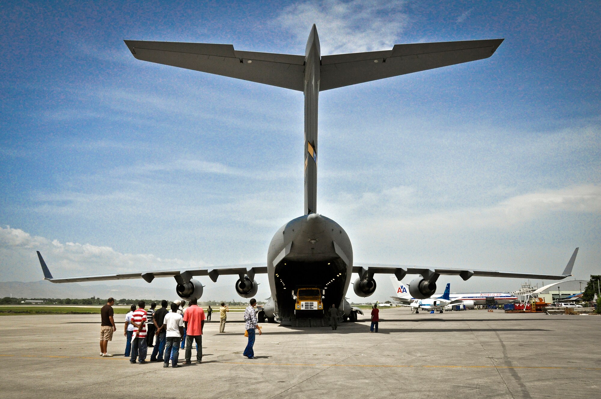 Humanitarian-aid workers wait for a dump truck to roll off the ramp of a C-17 Globemaster III July 1, 2011, in Haiti, during an aid mission. (U.S. Air Force photo/Staff Sgt. Rashard Coaxum) 