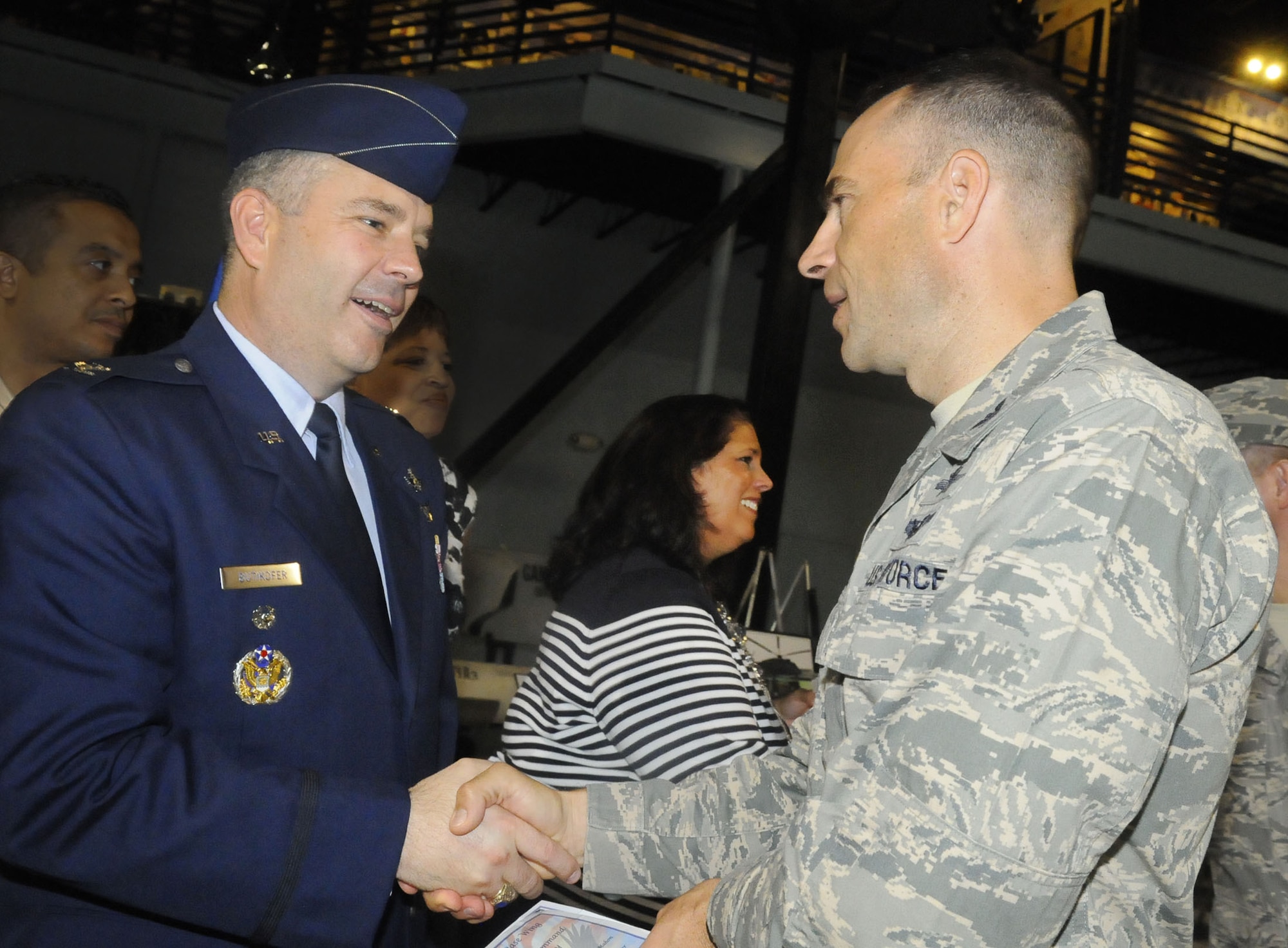 Colonel Mitchel H. Butikofer, 78th Air Base Wing commander, shakes hands with Col. Kevin Krause, 5th Combat Communications commander. Col. Butikofer and his wife Leslie, center, were welcomed at a reception after the change of command ceremony. U. S. Air Force photo by Sue Sapp