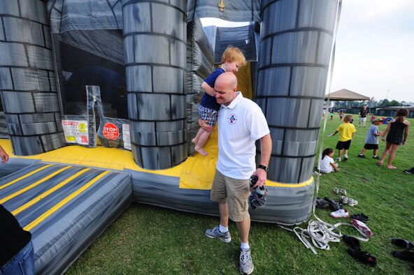 SEYMOUR JOHNSON AIR FORCE BASE, N.C. – Master Sgt. Rocky Casto picks up his son, Mick, after letting him play in one of the kid’s zone bouncy castles during the Independence Day celebration here, June 30, 2011. During the event, base organizations set up food and merchandise booths for fundraising. Casto, 4th Communications Squadron first sergeant, hails from Prescott, Ariz. (U.S. Air Force photo/Senior Airman Rae Perry/Released)