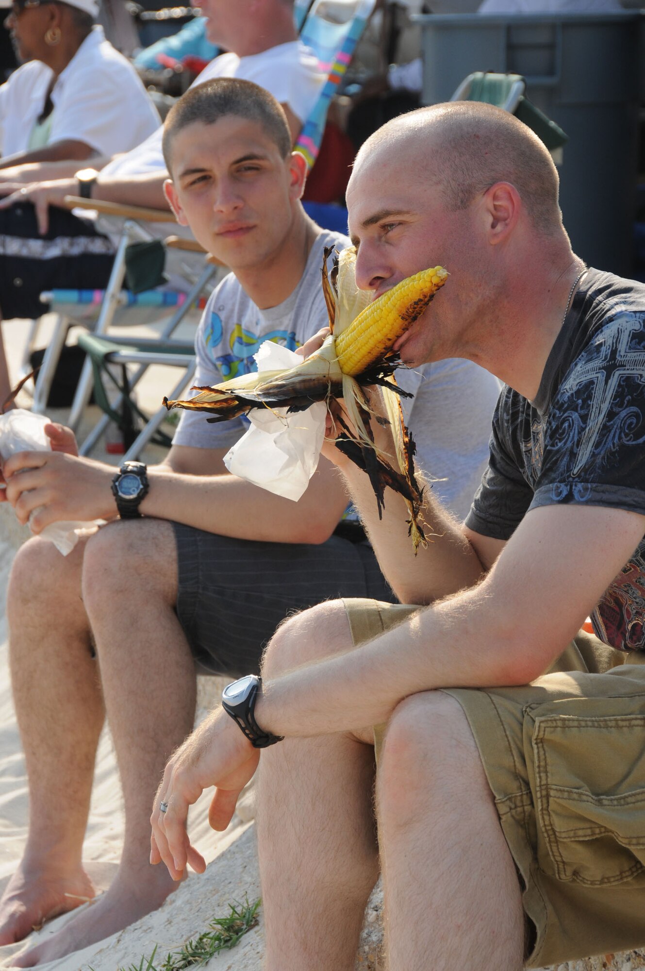 Airman Basic Alex Kurdo, and Airman 1st Class Matthew Bowen, 334th Training Squadron students, eat grilled corn on the cob during Keesler's 4th of July Beach Bash.  (U.S. Air Force photo by Kemberly Groue)