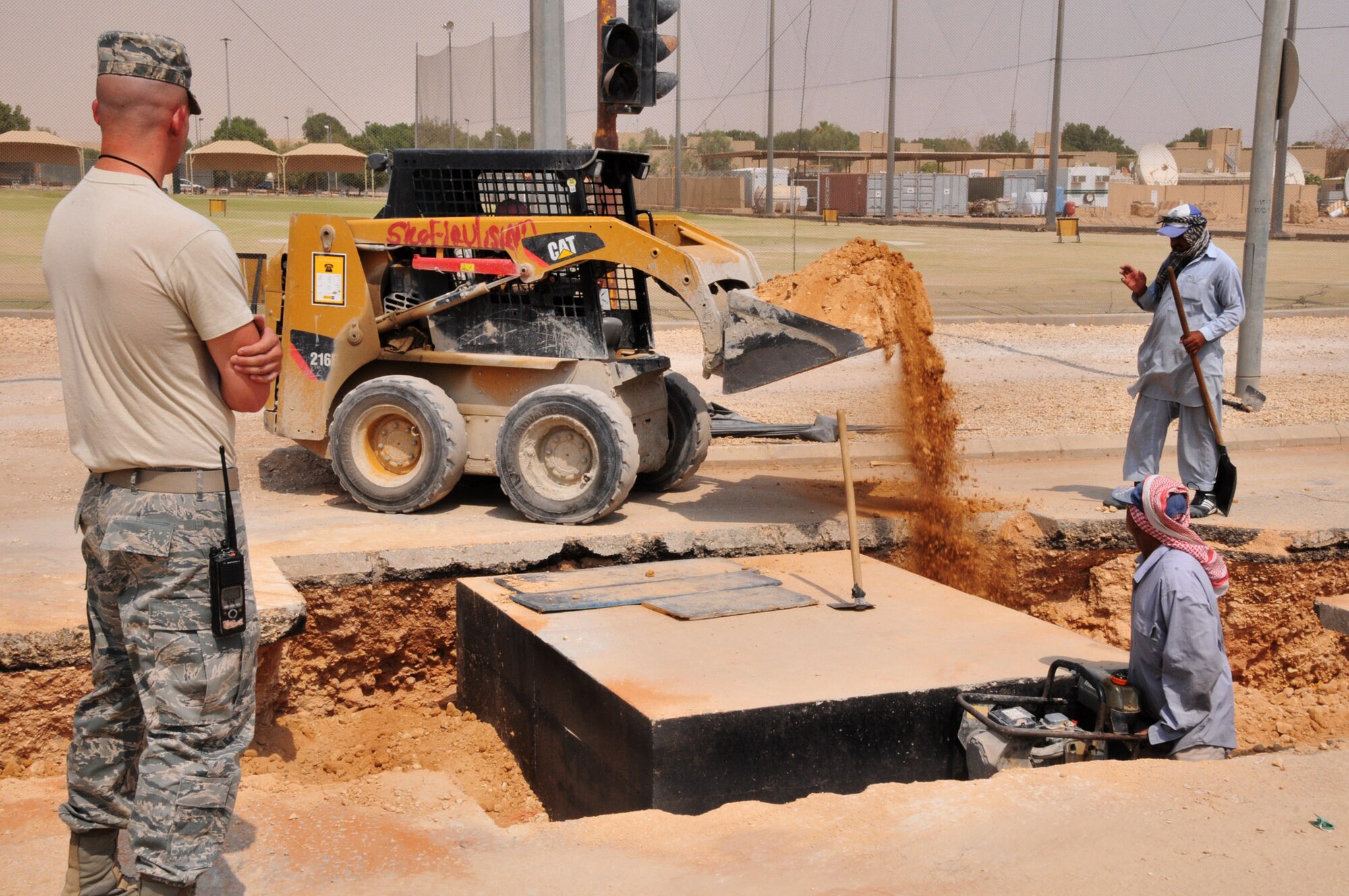 Senior Airman Patrick Meyers, a third country national escort deployed to the 64th Expeditionary Support Squadron's civil engineer escort flight, observes a backfill operation in a trench dug to lay part of a new water line on a deployed installation in Southwest Asia, June 28. Airman Meyers is deployed from Holloman AFB, N.M., and is one of nearly two dozen military members working with host nation contractors to complete a multi-year, $4.7 million upgrade to the base's water system. (U.S. Air Force photo/Master Sgt. Mike Hammond)