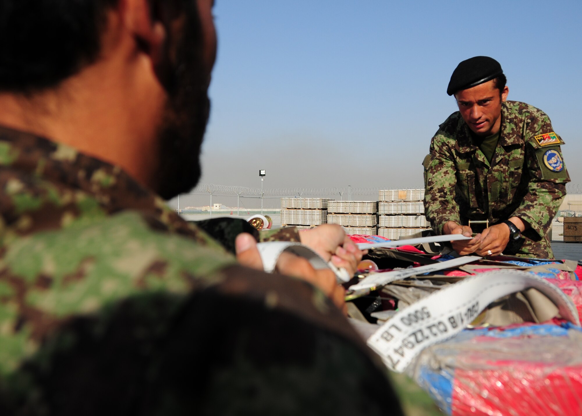 Two Afghan Air Force Airman prepare cargo netting for a recent shipment of AAF helicopter parts at Kabul International Airport, Kabul, Afghanistan, June 6, 2011. Deployed Airmen here at the 438th Air Expeditionary Wing, are responsible for setting the conditions for a professional, fully independent and operationally-capable Afghan Air Force. (U.S. Air Force photo by Senior Airman Amber Williams)