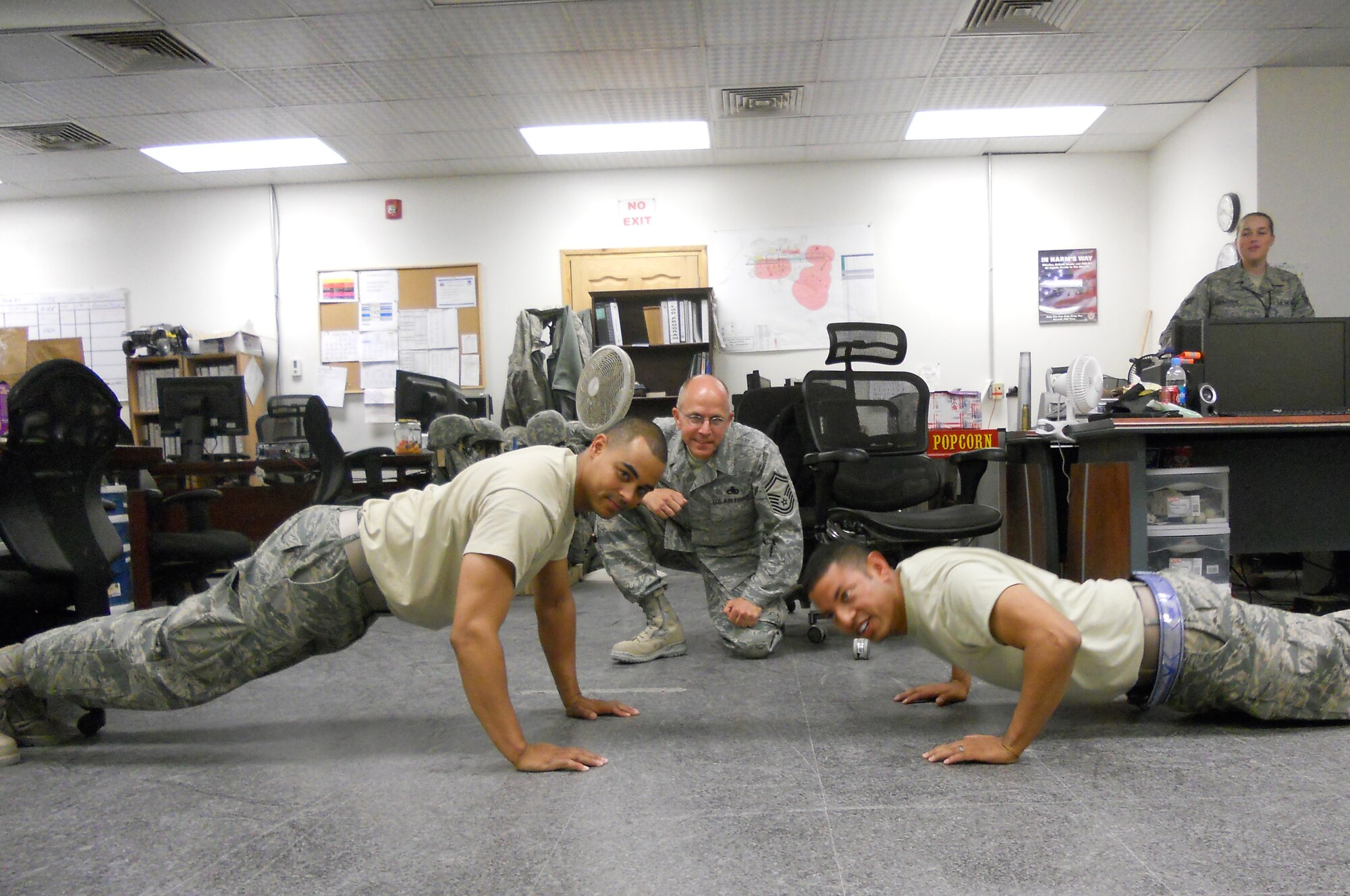 BAGRAM AIRFIELD, Afghanistan -- Tech. Sgt. Daniel Cain (left) and Master Sgt. Frank Espinoza (right), 455th Expeditionary Maintenance Group Quality Assurance, do pushups in front of Senior Master Sgt. Kelly Norris, 455th EMXG QA, for the Wounded Warrior Project here, July 6, 2011.  If you would like more information on the Wounded Warrior Project, visit www.woundedwarriorproject.org.  If you would like to contribute to the program contact Sergeant Cain at daniel.cain@bgab.afcent.af.mil. (Courtesy Photo)
