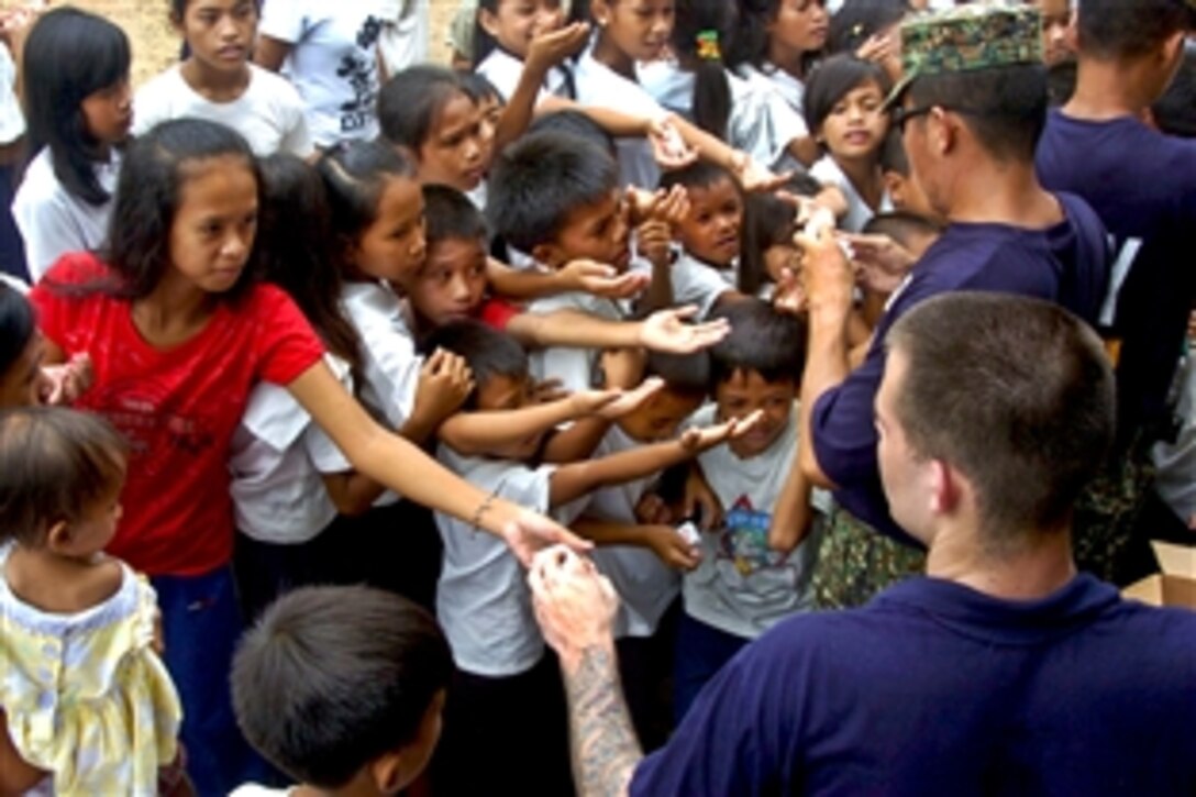 U.S. Navy Petty Officer 3rd Class Kyle Chrisman, lower right, and his Philippine counterparts distribute dental floss and dental kits to children during a community service project at Apalaya Elementary School during Cooperation Afloat Readiness and Training in Puerto Princesa, Philippines, June 30, 2011. Chrisman is a gas turbine systems technician (electrical) assigned to the USS Howard. 