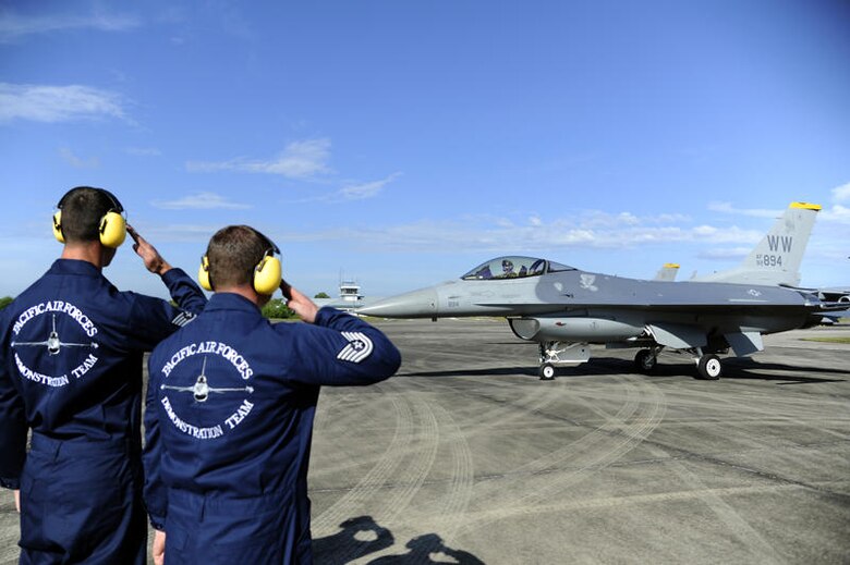 Brunei Darussalam --  Staff Sgt. Jonathan Crocer, left, and Tech. Sgt. Chad Miller, Pacific Air Forces Demonstration Team members, salute as Capt. Chris Nations, PACAF Demonstration Team pilot, taxis by during an air show practice for the 3rd Biennial Brunei Darussalam International Defense Exhibition at Rimba Air Base, Brunei July 3. BRIDEX provides an engaging and effective platform for leading manufacturers, suppliers and decision makers to deliberate on military solutions and showcase innovative technologies. (U.S. Air Force photo/Staff Sgt. Marie Brown/Released)