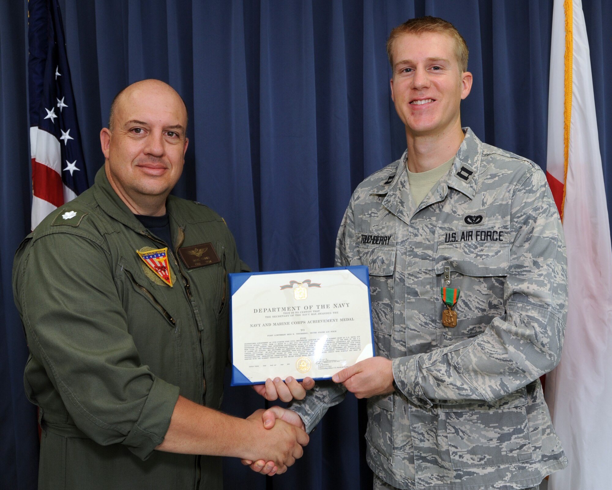 NAVAL AIR FACILITY MISAWA, Japan -- Navy Cmdr. Dave Cotts, Naval Air Facility Misawa Executive Officer, presents Air Force Capt. Reid Touchberry, 35th Civil Engineering Squadron Programming Element Chief, with the Navy and Marine Corps Achievement Medal July 6. Captain Touchberry was awarded the medal for his leadership in restoring electricity to the base following the March 11 earthquake and tsunami. Captain Touchberry coordinated a joint engineering task force that delivered 247 generators to facilities around the base. (U.S. Navy photo by Mass Communication Specialist 1st Class Matthew M. Bradley/Released)