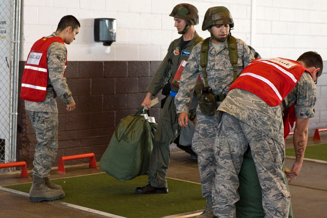 Airmen working on baggage crews take duffle bags from mobility line participants during a Phase I Operational Readiness Exercise at Ellsworth Air Force Base, S.D.,  June 22, 2011. The bags were inspected as part of a simulated deployment out-processing. (U.S. Air Force photo/Airman Alystria Maurer/Released)