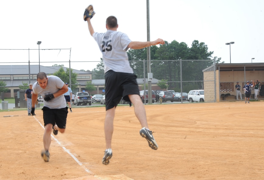 Edwin Donato, 723rd Aircraft Maintenance Squadron, sprints to first base as Lanny Shupe, 23rd Component Maintenance Squadron, jumps to catch the ball during an intramural softball game at Moody Air Force Base, Ga., July 6, 2011. The umpire called Donato safe as he helped 723rd AMXS win the game 12-3. (U.S. Air Force photo by Airman 1st Class Paul Francis/Released)