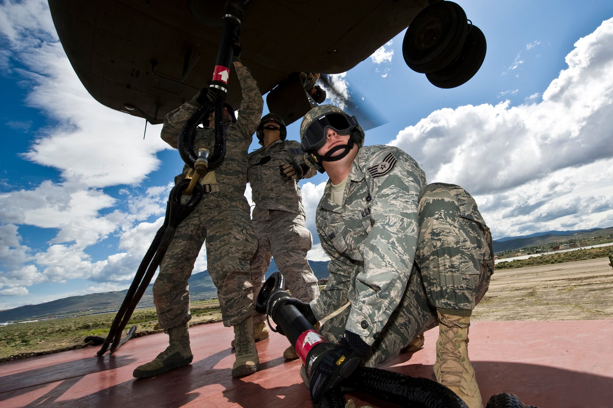 Tech. Sgt. Chris Kruze (foreground) stands by while Staff Sgt. Troy Hollis and Staff Sgt. Jeremy Lowe attach a storage container to a Nevada Army National Guard CH-47 Chinook helicopter June 28, 2011, during airdrop and sling-load training at the Senator Harry Reid Readiness and Training Center near Stead, Nev. Kruze and Lowe are airborne vehicle equipment craftsmen. Hollis is an airborne vehicle maintenance journeyman. All three NCOs are assigned to the 820th RED HORSE Squadron. (U.S Air Force photo/Senior Airman Brett Clashman)