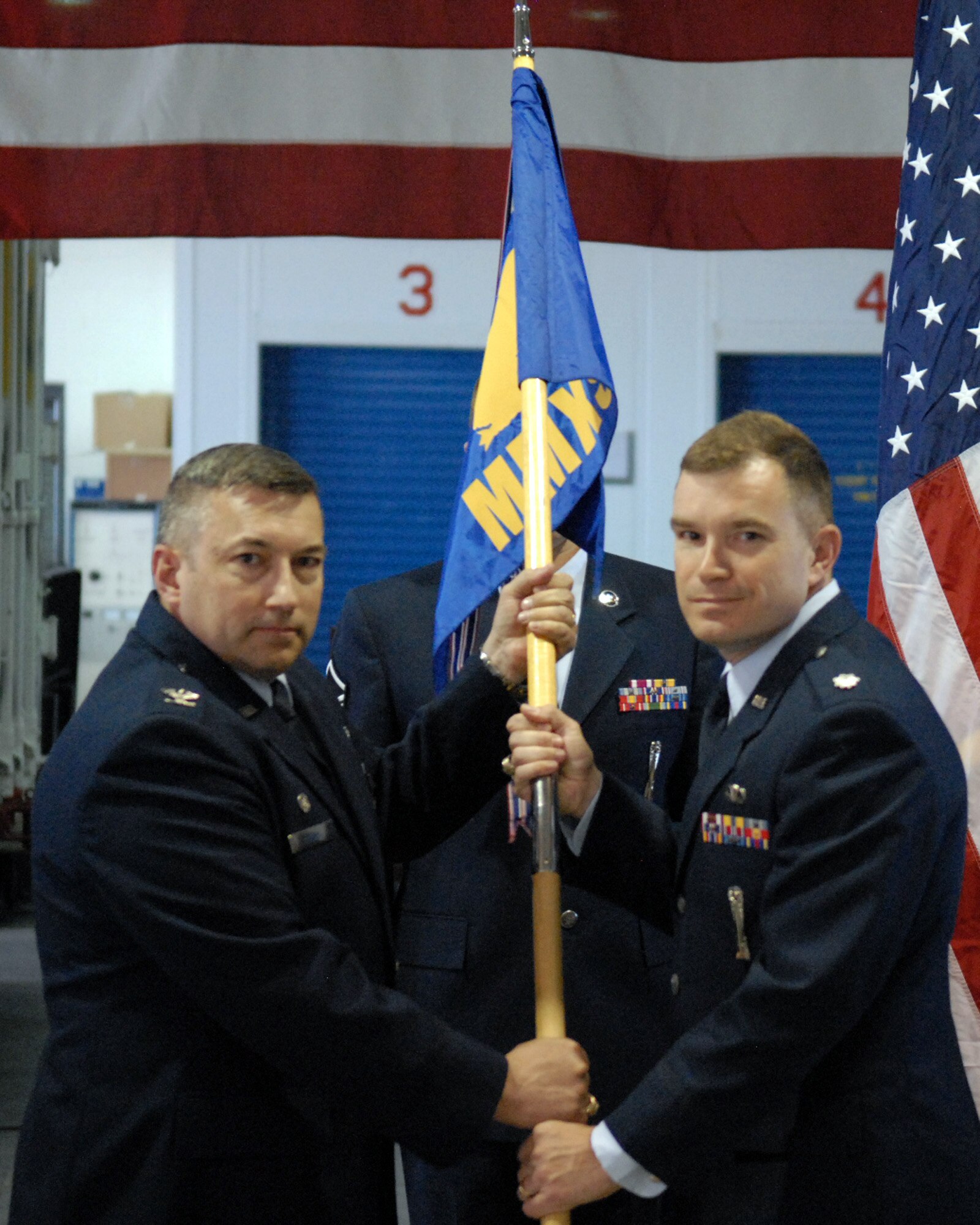 Lt. Col. William Barrington, Jr., 90th Missile Maintenance Squadron commander, accepts the guidon from Col. Don Adams, 90th Maintenance Group commander, for the 90th MMXS during the change-of-command ceremony held in Bldg. 1235 Wednesday. (U.S. Air Force photo by Blaze Lipowski)