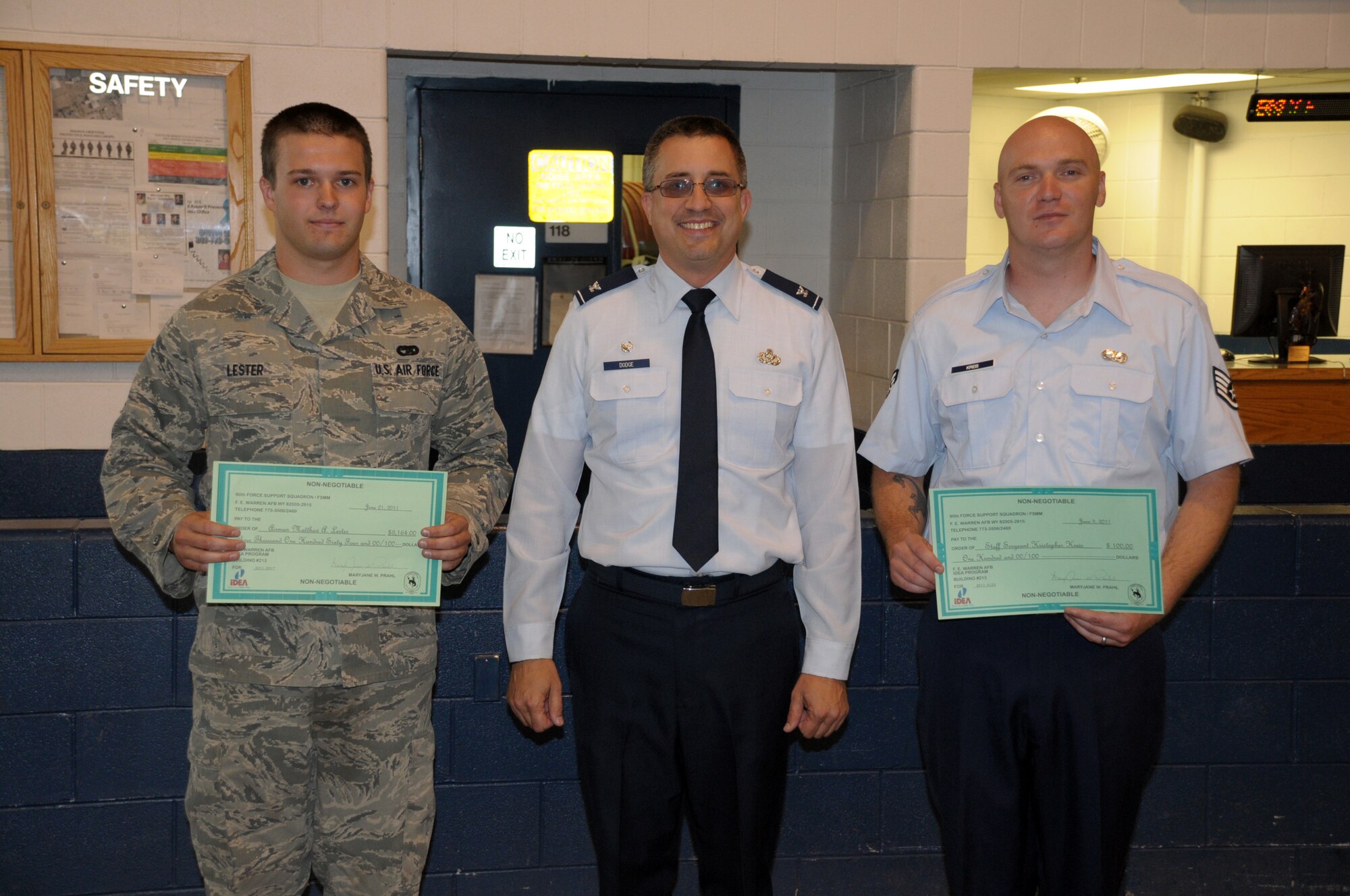 Col. Timothy Dodge, 90th Mission Support Group commander, presents checks for the Air Force Innovative Development through Employee Awareness program to Staff Sgt. Kristopher Kreis and Airman Matthew Lester, both from the 90th Logistics Readiness Squadron. Orlando Cepeda, 90th LRS, was also recognized by the IDEA program. The checks for Sgt. Kreis and Mr. Cepeda were given for modifications made to the seatbelts on Bear Cat seats, Airman Lester was presented the award for his improvements to HMMWV 24 volt direct current electric heaters. (U.S. Air Force photo by Blaze Lipowski)