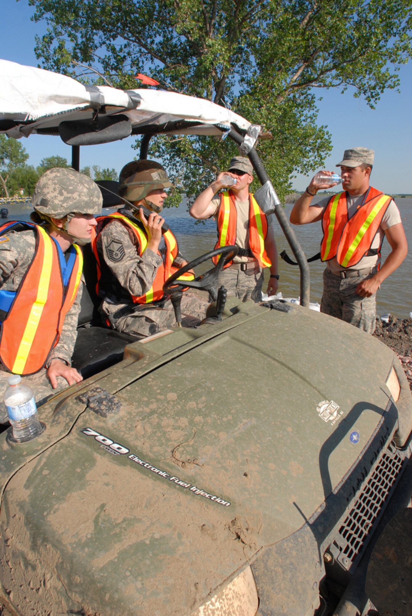 DAKOTA DUNES, S.D. - Sgt. Stephanie Johnson (left) from Jasper, Minn., a member of Medical Command based out of Rapid City and Master Sgt. Angela Pesicka from Parker, a member of the 114th Fighter Wing, Medical Group, pull up in their all-terrain vehicle to offer water to levee patrol members here June 28.  The South Dakota National Guard Soldiers and Airmen are patrolling the levee to monitor for weaknesses which might allow the flooding Missouri River to break through.  (Photo by Tech. Sgt. Quinton Young)(RELEASED)