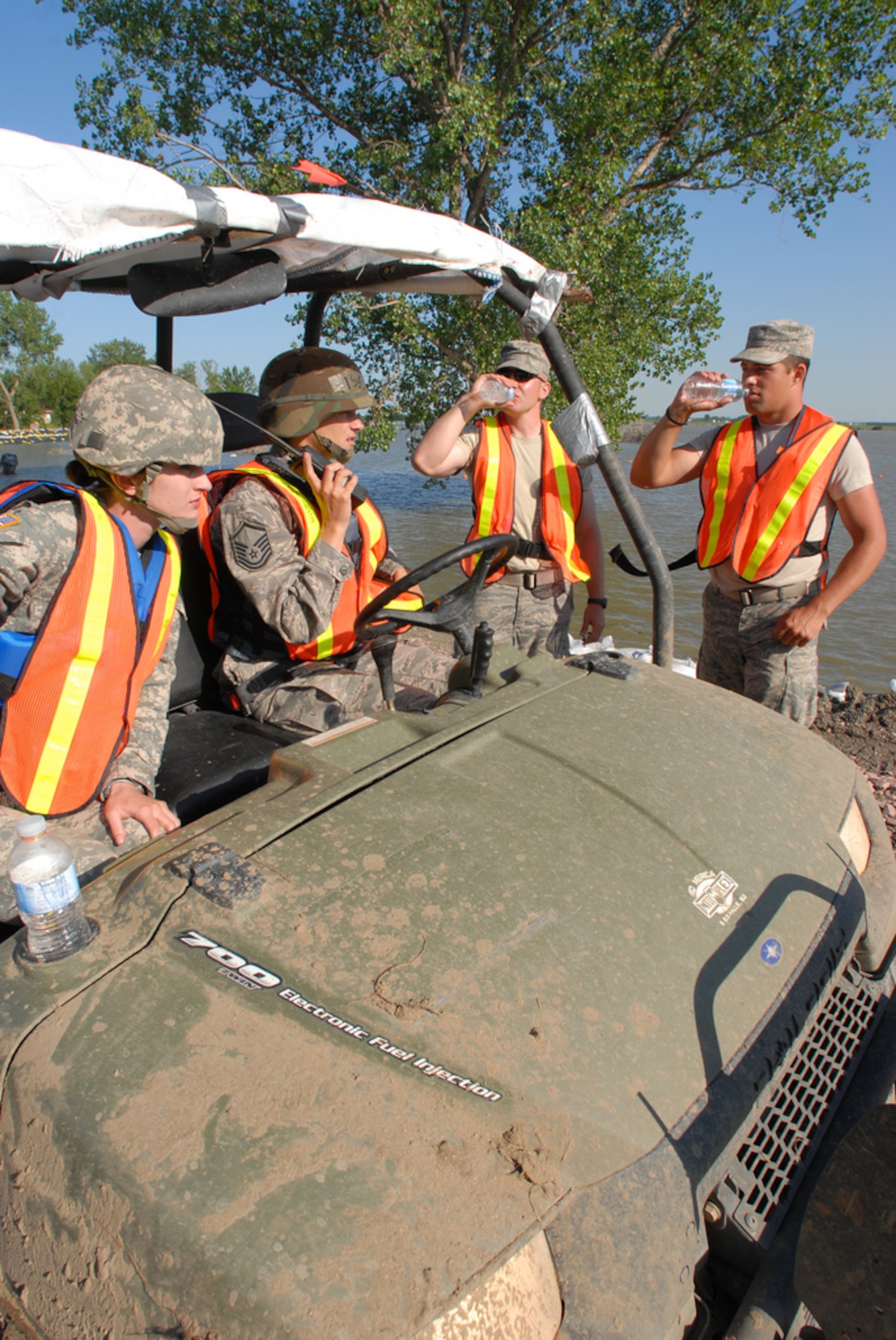 DAKOTA DUNES, S.D. - Sgt. Stephanie Johnson (left) from Jasper, Minn., a member of Medical Command based out of Rapid City and Master Sgt. Angela Pesicka from Parker, a member of the 114th Fighter Wing, Medical Group, pull up in their all-terrain vehicle to offer water to levee patrol members here June 28.  The South Dakota National Guard Soldiers and Airmen are patrolling the levee to monitor for weaknesses which might allow the flooding Missouri River to break through.  (Photo by Tech. Sgt. Quinton Young)(RELEASED)