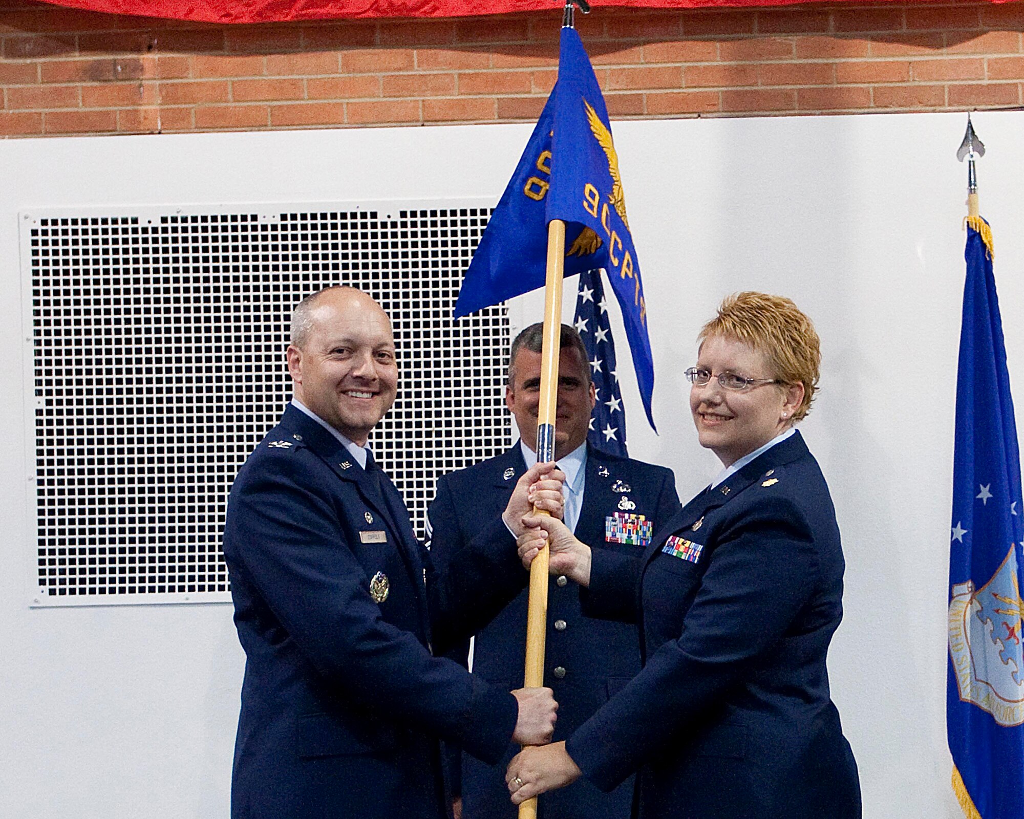 Maj. Christine Millard, 90th Comptroller Squadron commander, accepts the guidon from Col. Christopher Coffelt, 90th Missile Wing commander during a change-of-command ceremony in the Fall Hall Community Center Wednesday. (U.S. Air Force photo by Matt Bilden)