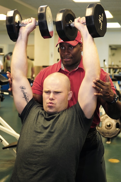 Staff Sgt. David Johnson finishes a lifting set while Omar Acosta spots him. Johnson is a gym operations manager assigned to the 375th Force Support Squadron at Scott Air Force Base, Ill. Acosta is a personal trainer at the Scott AFB gym. (U.S. Air Force photo/Staff Sgt. Teresa M. Jennings)
