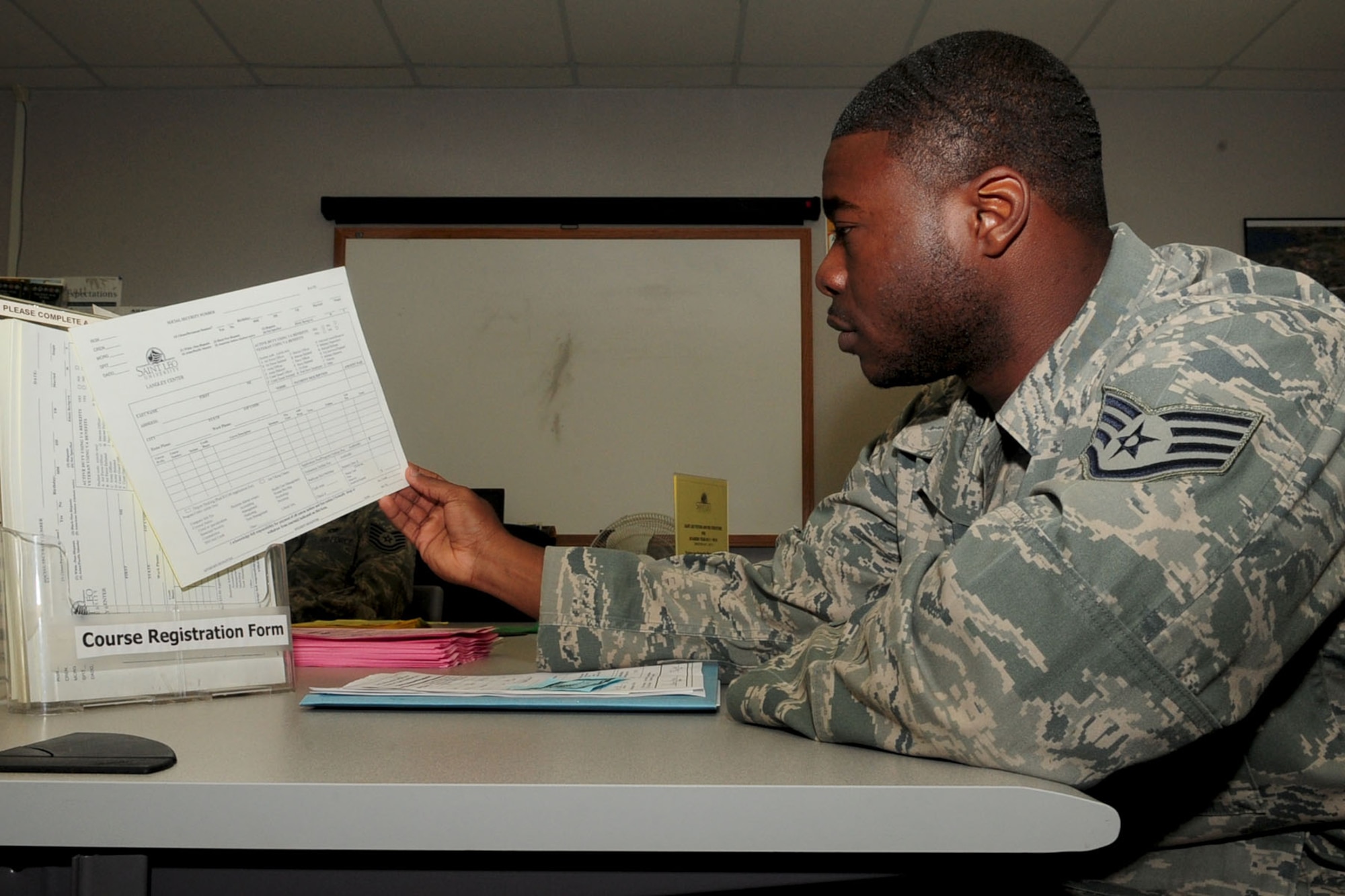 Staff Sgt. Soloman Jones, 633rd Aeromedical Squadron health service manager, picks out a Saint Leo University registration form at the Education Center at Langley Air Force Base, Va., July 7, 2011. The Education Center provides classes from various colleges and universities to assist servicemembers in obtaining their Community College of the Air Force or civilian degree. (U.S. Air Force photo by SSgt Ashley Hawkins/Released)