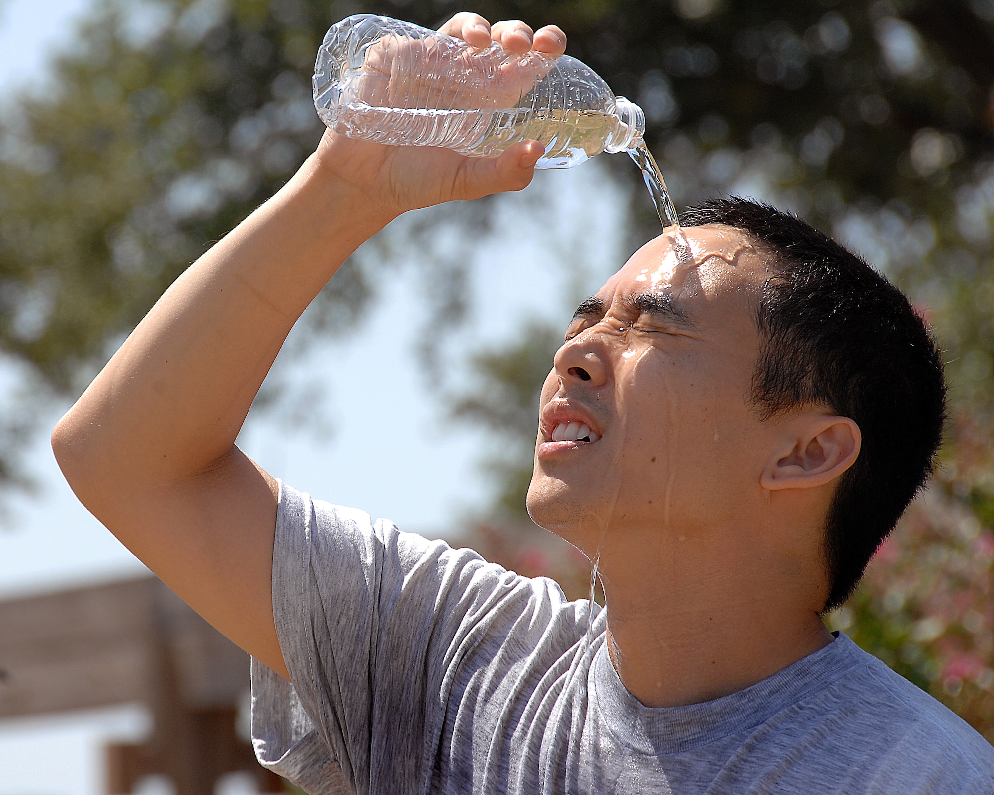 Senior Airman Kevin Iinuma poors water over his head to cool off after exercising outside Wilford Hall Medical Center July 5. Exercising in extreme heat is not recommended and certain precautions should be taken to prevent heat related illnesses. Airman Iinuma is a medical photographer for the 59th Medical Wing.  (U.S. Air Force Photo/SSgt Josie Walck)