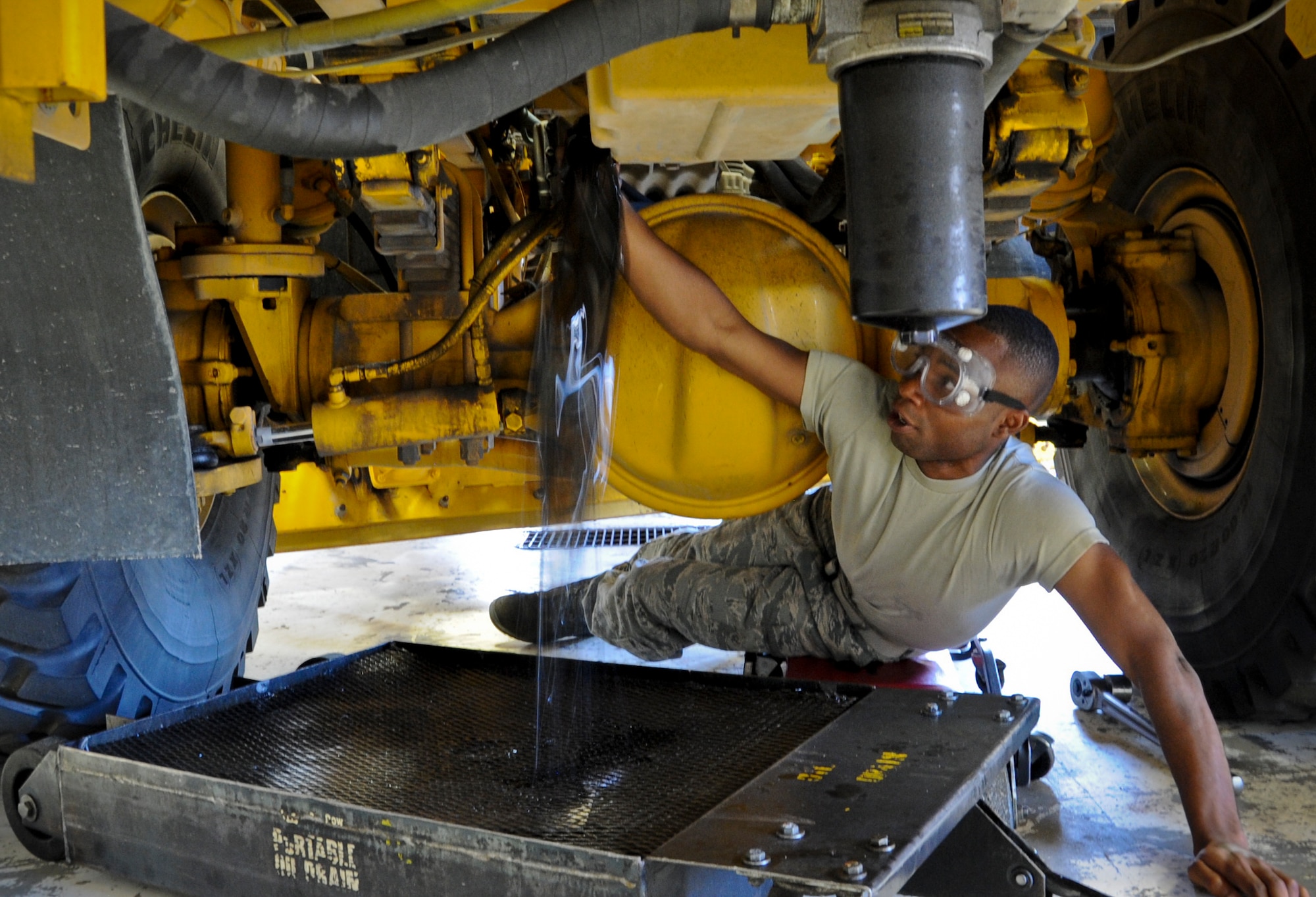 JOINT BASE MCGUIRE-DIX-LAKEHURST, N.J. -- Airman 1st Class Jhonny Vil, 87th Logistics Readiness Squadron, unscrews the plug of an oil tank onboard a snow plow at the 87th LRS vehicle maintenance shop. Vil and other vehicle maintenance specialists do summer-time re-builds on the snow plows to prepare them for the winter season. (U.S. Air Force photo by Airman 1st Class Dennis Sloan/Released)